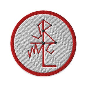 May include: Circular embroidered patch with a white centre and a red border. The design features a red geometric symbol with black accents. The patch has a textured appearance.