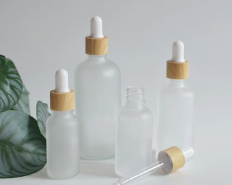 May include: Four frosted glass bottles with wooden caps and droppers. The bottles are different sizes and are arranged on a white surface. The text "Only 4 Creations" is visible in the bottom left corner of the image.