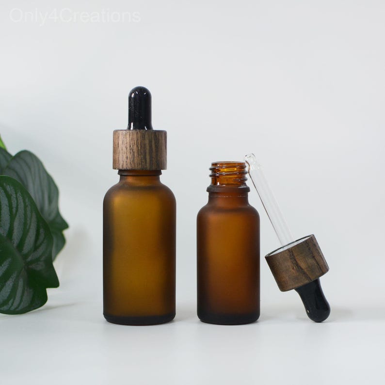 May include: Two amber glass bottles with droppers and wooden caps. The bottles are frosted and have a matte finish. The droppers are clear glass and the caps are dark brown wood.