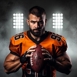 May include: A football player in an orange and black jersey with the number 99 on it, holding a brown football. The player is standing in front of a dark background with spotlights.