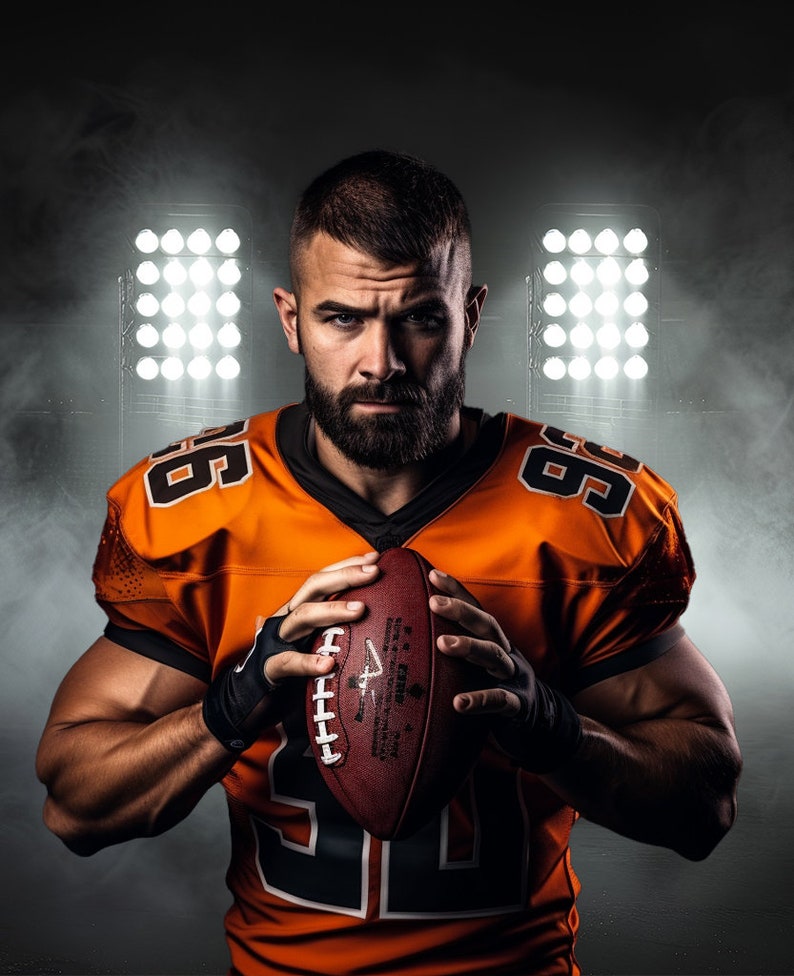 May include: A football player in an orange and black jersey with the number 99 on it, holding a brown football. The player is standing in front of a dark background with spotlights.