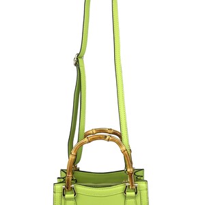 May include: A lime green leather handbag with a bamboo top handle and a long shoulder strap.