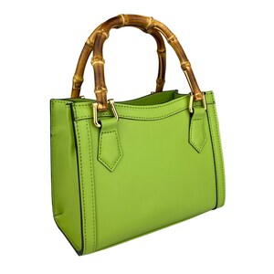 May include: A bright green leather handbag with a bamboo top handle. The bag has a structured shape and gold hardware.