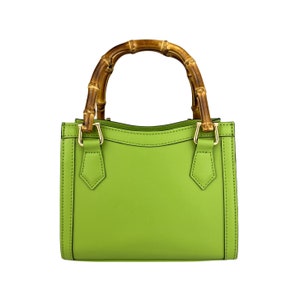 May include: A bright green leather handbag with a bamboo top handle. The bag has a structured shape and gold hardware.