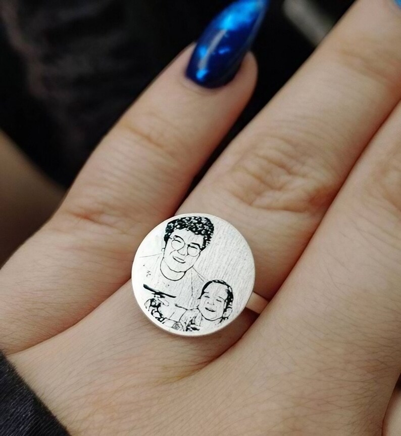 May include: A silver ring featuring a round engraved image of a woman and a child. The image is in black and white.