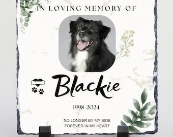 May include: A white slate memorial plaque with a black and white photo of a dog, the words "IN LOVING MEMORY OF", "Blackie", "1998-2024", "NO LONGER BY MY SIDE", and "FOREVER IN MY HEART", and a paw print and bone heart graphic.