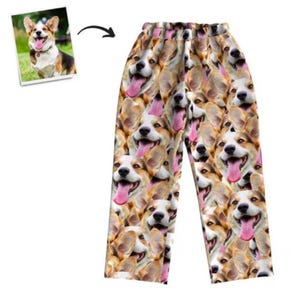 Puede incluir: Pantalón de pijama blanco con un patrón repetido de la cara de un perro. El perro tiene pelo marrón y blanco y saca la lengua.