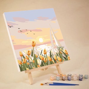 May include: A paint by numbers kit featuring a sunset scene with a sailboat and yellow tulips. The kit includes a canvas, paint pots, and brushes.
