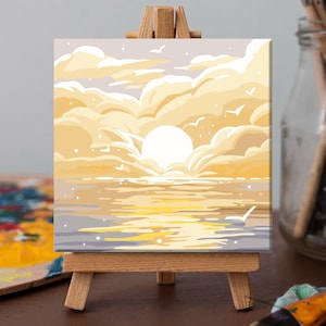 May include: A painting on canvas depicting a sunset over a calm body of water. The sky is filled with fluffy, yellow clouds and the sun is a bright white circle. The water is a light blue with a golden reflection of the sun.