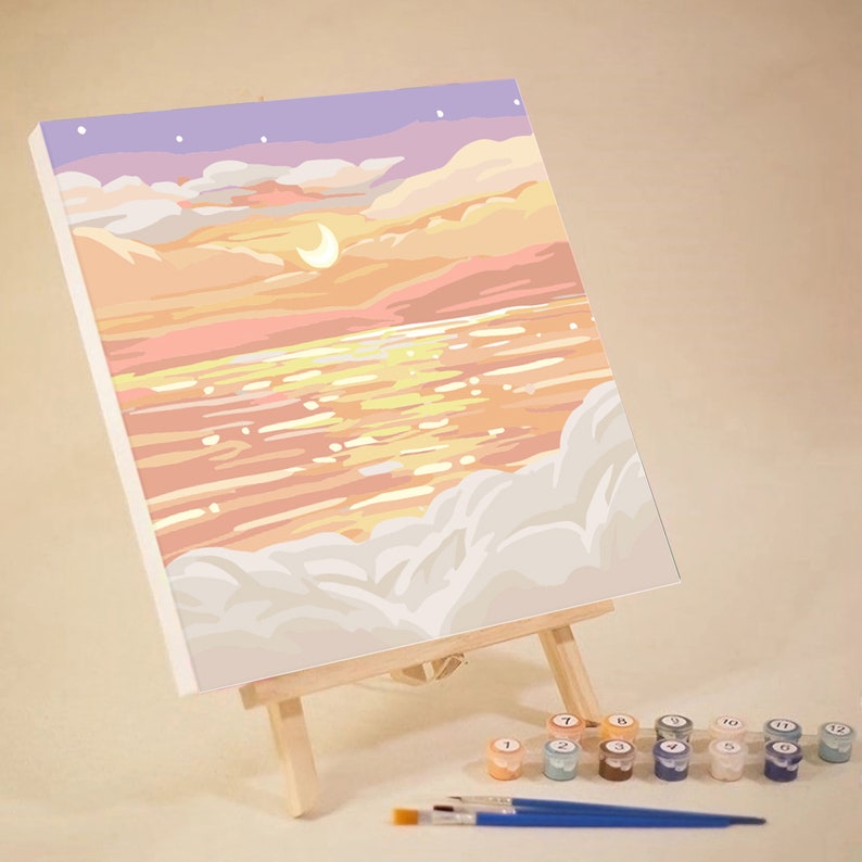 May include: A paint by numbers kit featuring a sunset over a body of water with clouds in the foreground. The kit includes a canvas, paints, and brushes.