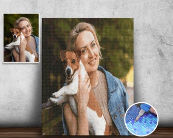 May include: A woman with a white and brown dog in her arms. The woman is smiling and the dog is looking at the camera. The background is a blurred green and brown.