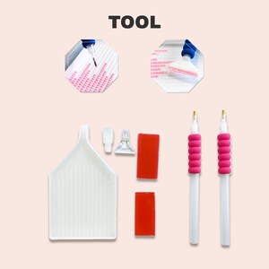 May include: Diamond painting tools including two pink-handled pens with clear tips, a white tray with ridges, two red sticky pads, a clear plastic tool with a handle, and a clear plastic tool with a handle and a suction cup.