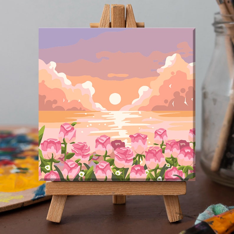 May include: A canvas painting depicting a sunset over a body of water with pink flowers in the foreground. The sky is a soft pink and purple with fluffy clouds. The sun is setting in the distance, casting a warm glow on the water. The flowers are in full bloom and add a touch of colour to the scene.