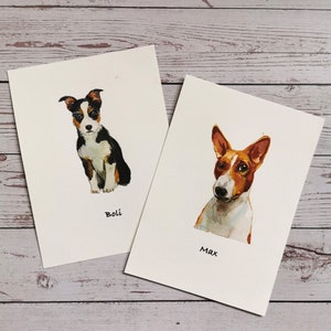 May include: Two watercolor paintings of dogs on white card stock. The first painting is of a black and white dog named "Boli". The second painting is of a brown and white dog named "Max".