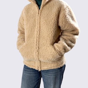 Oatmeal beige unisex merino wool jacket with full zip and high collar, displayed on model against neutral beige background.