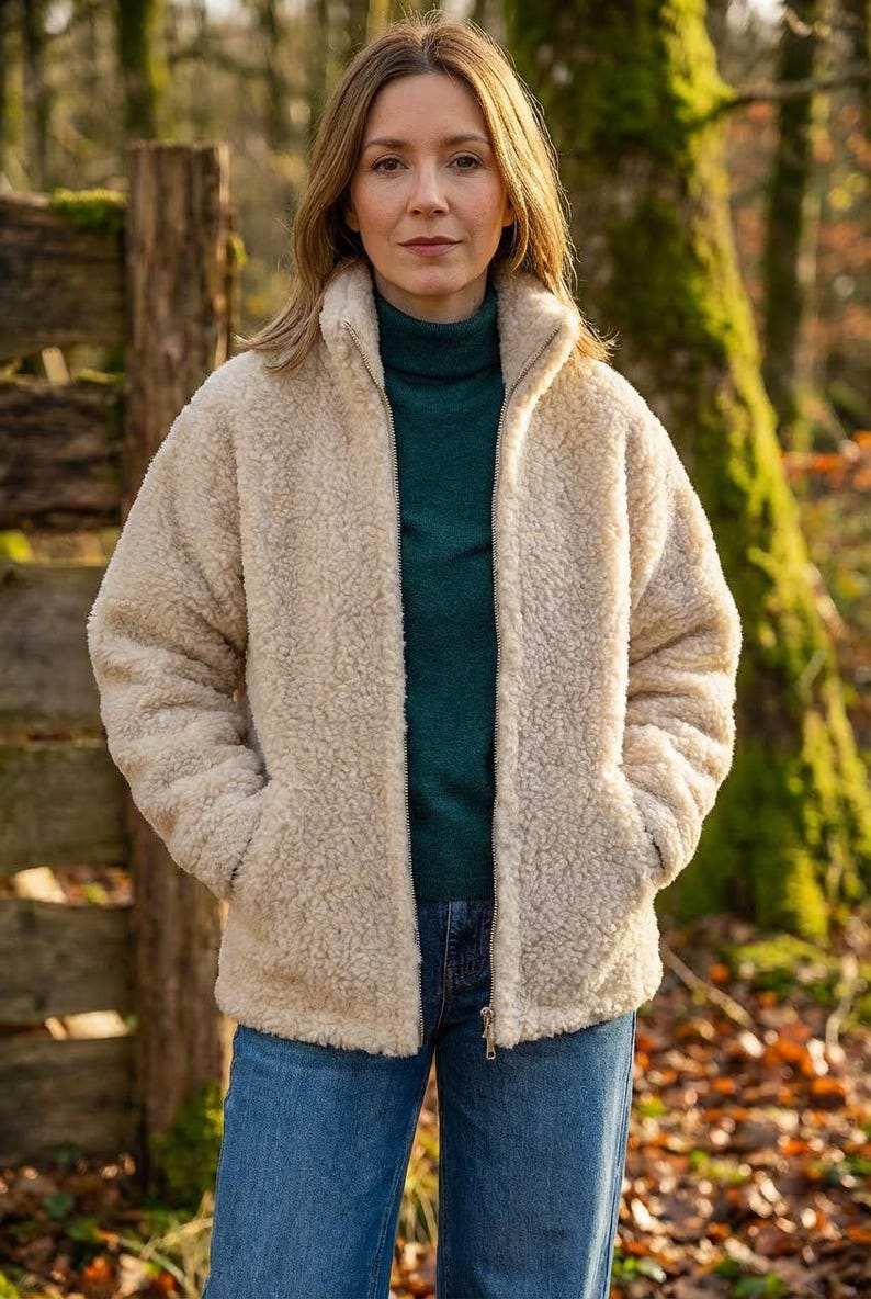Female model wearing oatmeal merino wool jacket outdoors showing styling and fit on woodland background