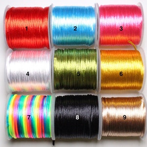 May include: Nine spools of different colored satin cord, numbered 1 through 9. The cords are wound around spools with clear plastic cases.