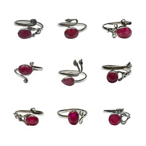 Peut inclure: Neuf bagues en argent avec des pierres précieuses rouges. Les bagues ont des designs différents, y compris des motifs de feuilles et de volutes.