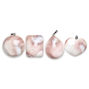 Peut inclure: Quatre pendentifs en coquille rose et blanche avec des boucles en métal argenté. Les pendentifs sont en forme de cercle, de carré, de larme et de cœur.