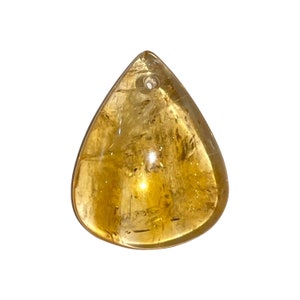 Pode incluir: Um pingente de citrino translúcido em forma de gota, com um pequeno orifício na parte superior para enfiar. A pedra preciosa polida tem um tom amarelo dourado quente e uma superfície lisa. O pingente é ideal para fazer joias.
