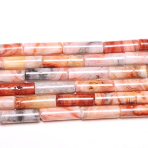 Peut inclure: Un brin de perles d'agate, chaque perle est un cylindre avec un motif unique de tourbillons roses, blancs et bruns.