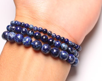 May include: A stack of blue and white patterned beaded bracelets on a person's wrist.
