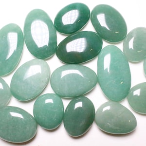Può includere: Una collezione di pietre di avventurina verde lisce di forma ovale. Le pietre sono lucidate e hanno un colore verde chiaro.