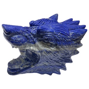 Op de afbeelding: Een gesneden wolfskop sculptuur gemaakt van blauwe lapis lazuli steen. Het beeld is gedetailleerd met een grommende uitdrukking en textuurhaar.