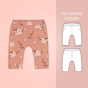 May include: Peach-colored baby pants with a floral pattern featuring white flowers and brown stems. The pants have two pockets and a comfortable, relaxed fit. The image also includes a PDF sewing pattern.