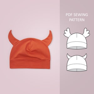 Puede incluir: Un patrón de costura PDF para un gorro de diablo rojo y blanco. El patrón incluye instrucciones para hacer un gorro con cuernos y una visera.