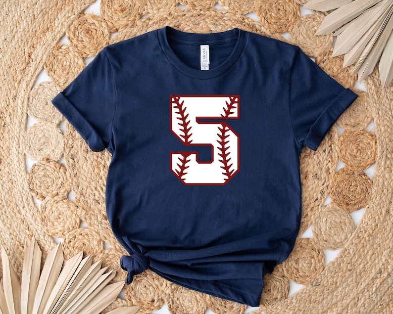 May include: Navy blue t-shirt with a white baseball-style number "5" in a red outline.