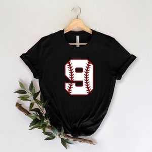 May include: Black t-shirt with a white baseball number 9 on a red baseball graphic.