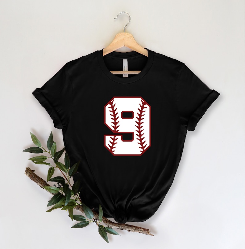 May include: Black t-shirt with a white baseball number 9 on a red baseball graphic.