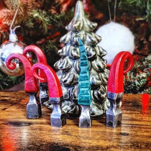 Peut inclure: Cinq ornements de chaussures d'elfes rouges et noirs avec un sapin de Noël en céramique vert et argent en arrière-plan.