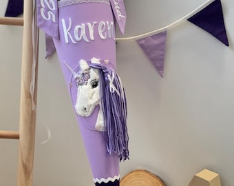 Könnte beinhalten: Ein lila-weißer Schultüte mit einem Einhorn-Motiv. Die Tüte hat ein weißes Band mit dem Text "Schulkind Karen 2025" darauf.