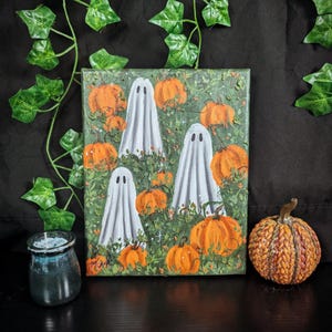 Könnte beinhalten: Ein Gemälde, das eine gruselige Halloween-Szene mit weißen Geistern in einem Feld mit orangefarbenen Kürbissen zeigt. Die Geister sind halbtransparent und haben einen schwachen Schein. Die Kürbisse sind über das Feld verteilt, und im Hintergrund befinden sich grüne Blätter und Ranken.