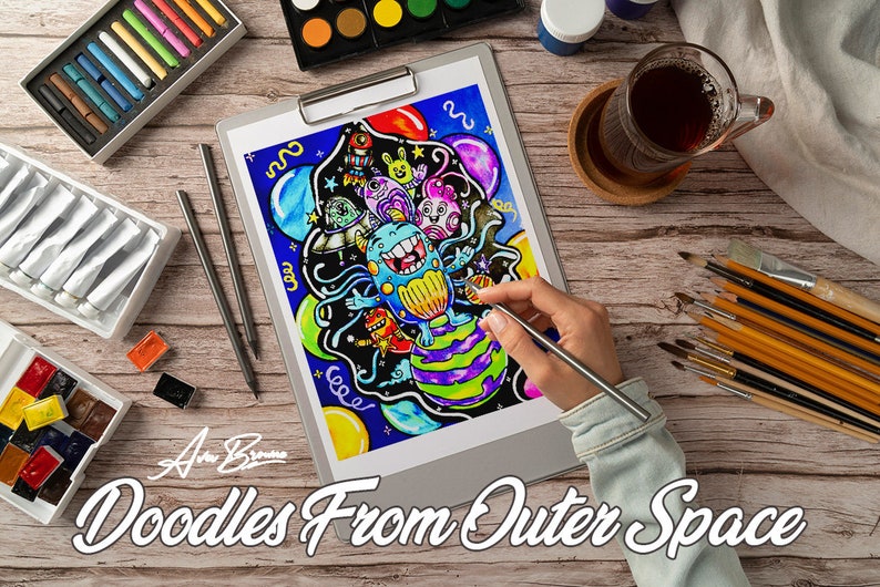 Peut inclure: Une illustration color&eacute;e de doodle art d'un monstre dans l'espace avec des plan&egrave;tes, des &eacute;toiles et des ballons. L'art est sur une feuille de papier blanche sur un presse-papiers. L'artiste utilise un stylo argent&eacute; pour ajouter des d&eacute;tails &agrave; l'illustration.