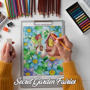 K&ouml;nnte beinhalten: Eine Person koloriert eine detaillierte Illustration einer Fee in einem Garten mit einem gelben Vogel in einem Vogelhaus. Die Illustration befindet sich auf einer Klemmbrett mit dem Text "Secret Garden Fairies". Die Person verwendet farbige Bleistifte und hat eine Vielzahl von Kunstmaterialien auf dem Tisch, darunter Wasserfarben, Pinsel und einen Radiergummi.