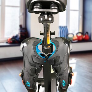 May include: Black cycling shoes with blue accents and a black bike seat attached to a black stand.