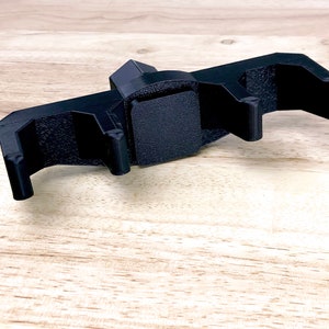 Pu&ograve; includere: Strumento in plastica nera con tre punte e una base quadrata. Lo strumento &egrave; progettato per tenere gli oggetti in modo sicuro.