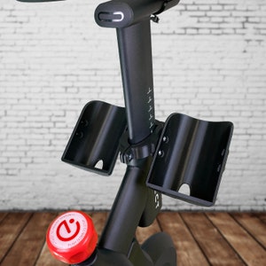May include: Black exercise bike with two black water bottle holders and a red knob with the text "Adjust to adjust tension, push down to stop".