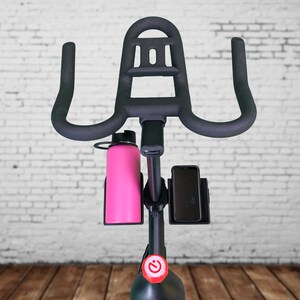 May include: Black stationary exercise bike with a water bottle holder and a phone holder. The bike has a red button on the front.