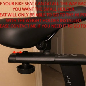 May include: Black bike seat with a numbered adjustment lever. The text on the image reads: "IF YOUR BIKE SEAT CAN GO ALL THE WAY BACK, YOU WANT THE SMALL HOLDER. THE SEAT WILL ONLY BE ABLE TO GO TO THE #6 POSITION WITH THE WEIGHT HOLDER INSTALLED. PLEASE CONTACT ME IF YOU NEED IT TO GO TO #7."
