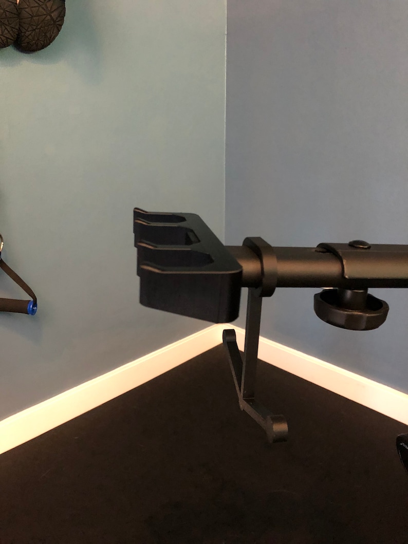 May include: Black metal weight plate holder with three slots. The holder is mounted on a black metal stand with a knob for adjusting the height.