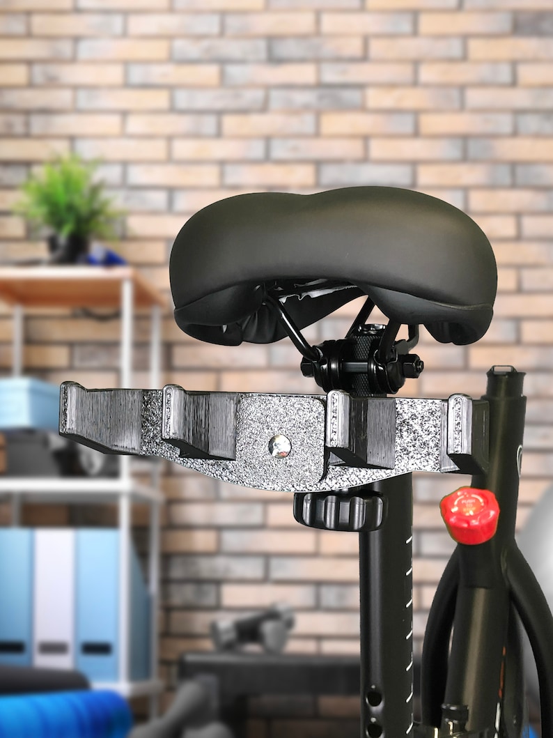 May include: Black exercise bike with a padded seat and a red knob. The bike has a black metal frame and a black seat.