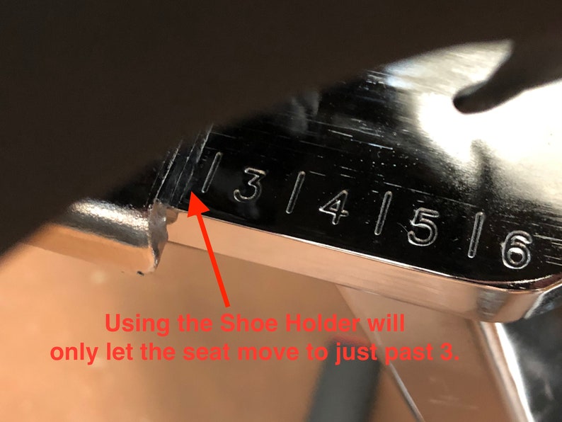 May include: Close-up of a silver metal ruler with numbers 3, 4, 5, and 6 marked on it. An arrow points to the number 3. The text "Using the Shoe Holder will only let the seat move to just past 3." is written below the ruler.