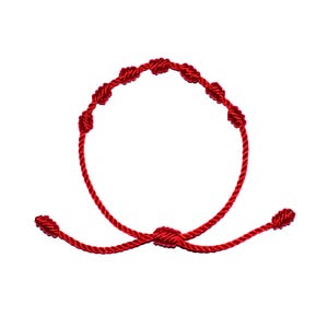 May include: A red knotted bracelet with multiple knots along the length of the bracelet.