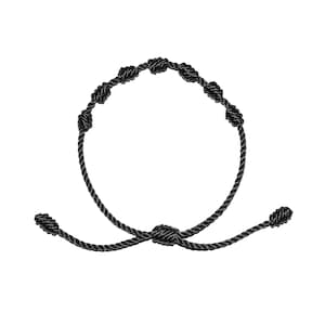 May include: A black knotted bracelet with silver accents. The bracelet is adjustable and has a sliding knot closure.