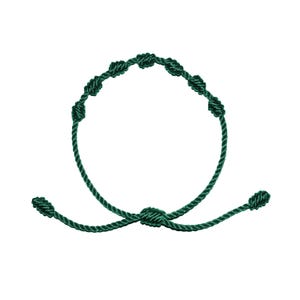 May include: Dark green knotted bracelet. The bracelet features a series of knots along the circular band, with adjustable knots at the ends. The bracelet is made of a dark green cord.