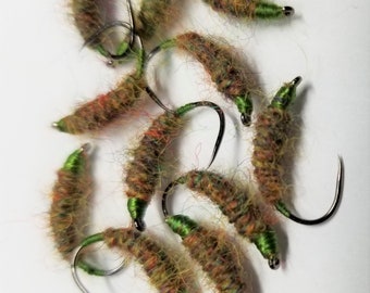 May include: A group of 10 green and brown fly fishing lures with a fuzzy texture. The lures are tied on hooks with a green thread.